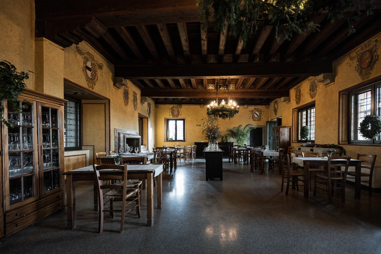 Sala interna della Casa della Contadinanza con travi a vista e stemmi affrescati